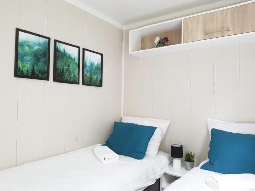 dwa łóżka w pokoju z trzema zdjęciami na ścianie w obiekcie Odpocznij sobie w mieście Radków