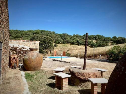 un jardín con bancos, un jarrón grande y una piscina en Casa Rural El Poleo, en Villaviciosa de Córdoba