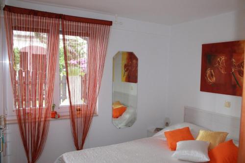 1 dormitorio con 1 cama con almohadas de color naranja y ventana en Ferienwohnung in Sabunike mit Terrasse, Klimaanlage, W-LAN (231-2), en Privlaka