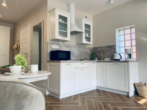 a white kitchen with white cabinets and a table at Apartamenty Kamienica Arte 4 in Ustka