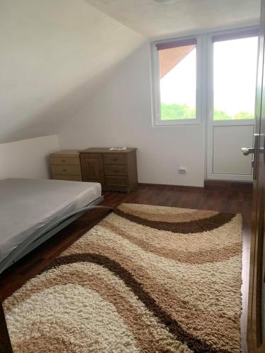 a bedroom with a bed with a rug and a window at Casa ANA in Geoagiu
