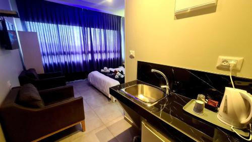a bathroom with a sink and a living room at Spat Hotel Ashdod in Ashdod
