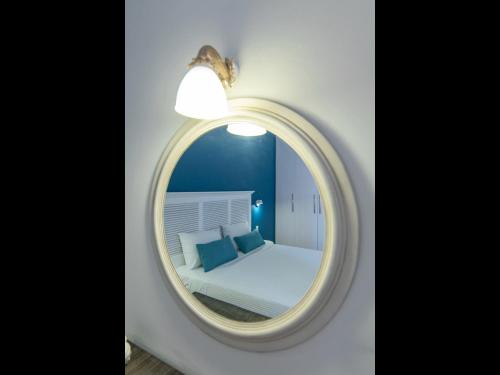 a mirror in a room with a bed and a light at FiscardoStudios in Fiskardho