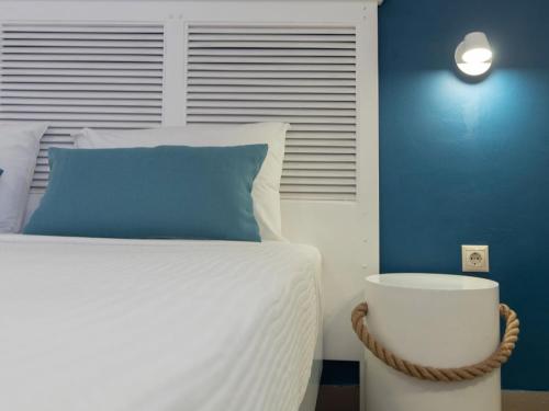 a bedroom with a white bed with a blue wall at FiscardoStudios in Fiskardho