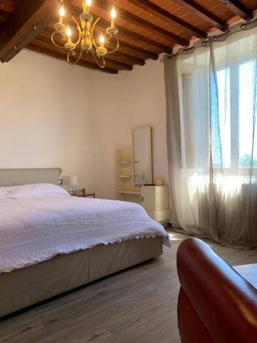 ein Schlafzimmer mit einem Bett, einem Kronleuchter und einem Fenster in der Unterkunft Fonte alle Ninfe B&B in Castiglione dʼOrcia