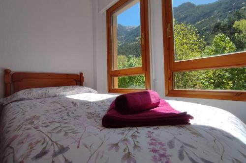 ein Bett mit einem rosa Hut in einem Zimmer mit Fenstern in der Unterkunft Martina , Estación de Canfranc in Canfranc-Estación