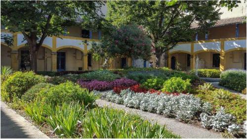 un jardin avec des fleurs devant un immeuble dans l'établissement Studio climatisé avec balcon face aux arènes d'Arles, à Arles