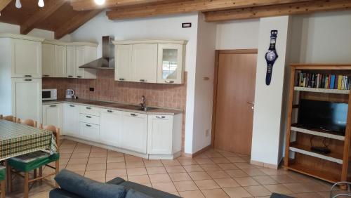una cucina con armadi bianchi, tavolo e TV di Cesa Stefi a Canazei