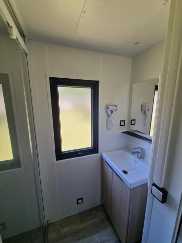 a bathroom with a sink and a window at Mobil Home XXL2 4 chambres - Camping Bordeaux Lac in Bruges