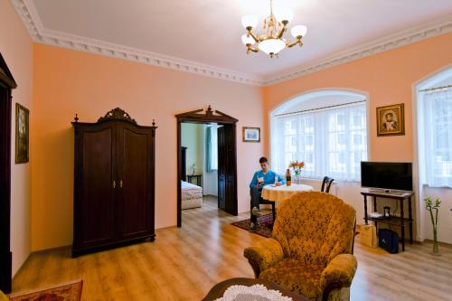 a man sitting at a table in a living room at Pension Napoleon in Karlovy Vary