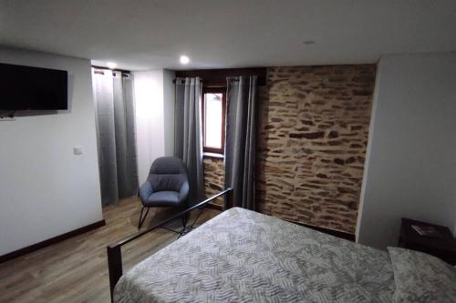 a bedroom with a bed and a chair and a television at Casinha da Fonte in Lamas de Podence