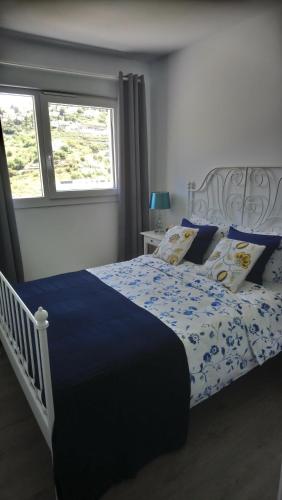1 dormitorio con 1 cama con edredón azul y ventana en Penthouse - Atico Playa Cabria Almunecar, en Granada