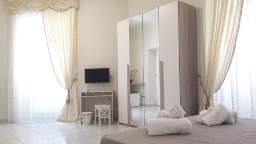- une chambre blanche avec un grand miroir et une télévision dans l'établissement Sweet Home Agropoli, à Agropoli