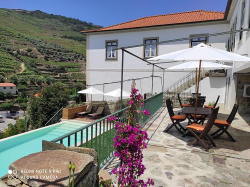a house with a swimming pool and a table and umbrella at Quinta da Travessa - Douro in Covelinhas