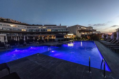 - une grande piscine avec des lumières bleues la nuit dans l'établissement Suite Home Porticcio, à Porticcio