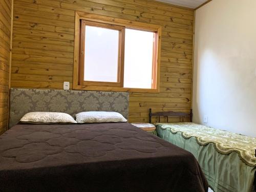 um quarto com uma cama num quarto com uma janela em Chalé no centro da Capital dos Canyons em Praia Grande