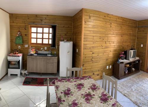 uma cozinha com paredes de madeira e um frigorífico branco em Chalé no centro da Capital dos Canyons em Praia Grande