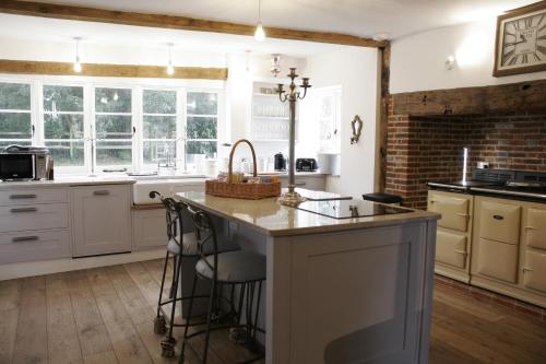 una cocina con armarios blancos y una gran isla en Church Farmhouse, Surrey, Sleeps 10, Large Garden en Crowhurst