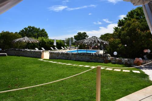 a yard with a swimming pool with chairs and umbrellas at Bed and Breakfast La Terrazza in Cisternino