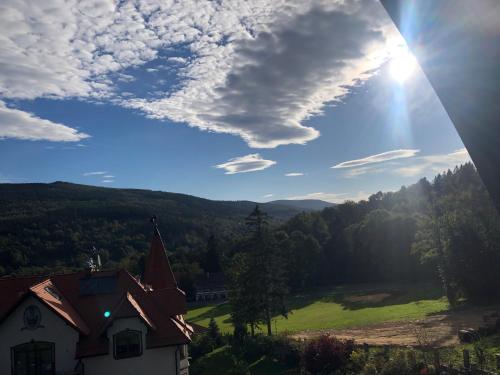 a house with a view of a green field and the sun at Boutique Hotel Sudetia - Medical & SPA in Świeradów-Zdrój