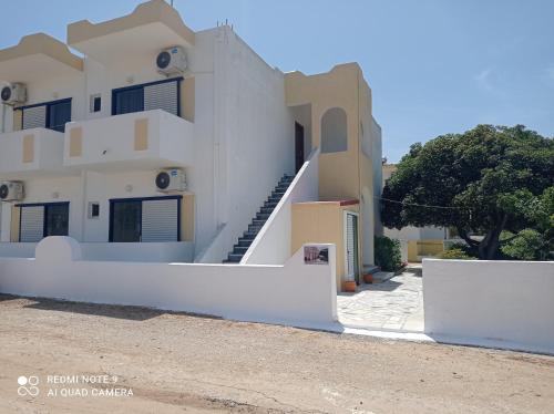 ein weißes Haus mit einer Treppe davor in der Unterkunft IASONAS APARTMENTS in Mastichari