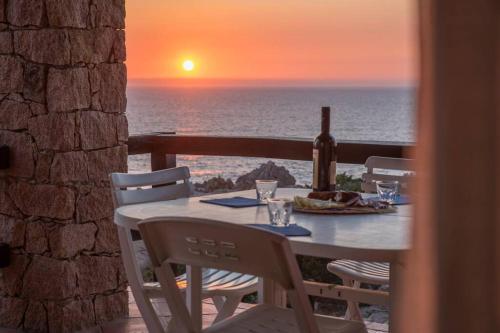 ein Tisch mit einer Flasche Wein auf einem Balkon mit Sonnenuntergang in der Unterkunft Casa Del Tramonto in Costa Paradiso