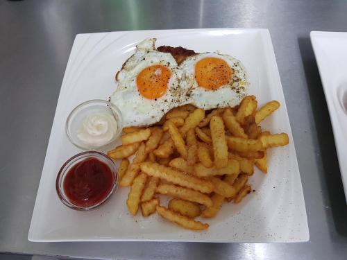 a plate of food with eggs and french fries at Tattoo PENSION mit Restaurant und Tattoo-Studio in Mörtschach