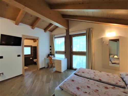 a bedroom with a bed and a desk and windows at B&B Il Germoglio in Castione Andevenno