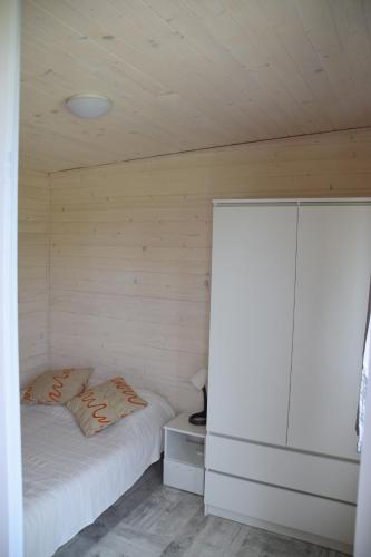 a small bedroom with a bed and a cabinet at Domek "Marla 1" in Żelistrzewo
