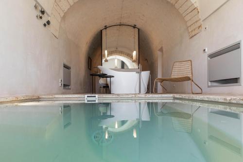 a swimming pool with a tub and a chair in a room at Il Sogno delle Benedettine in Ostuni