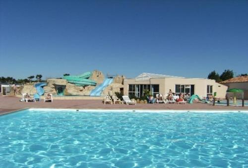 une piscine avec un parc aquatique en arrière-plan dans l'établissement Mobil-home Dan Dom, à Saint-Hilaire-de-Riez
