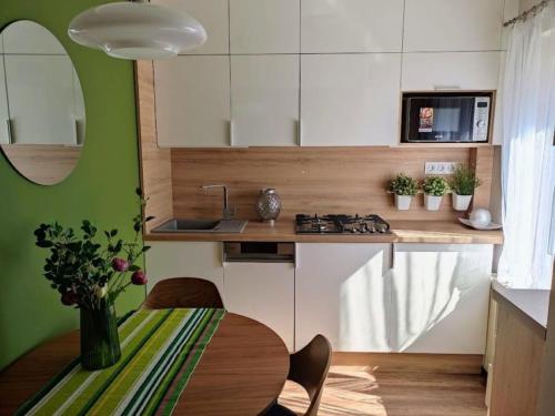 a kitchen with a table and a green wall at Libis Apartman in Bük