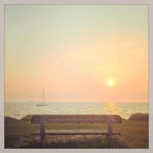 a bench in front of the ocean at sunset at Hotel Napoleon in Île dʼAix