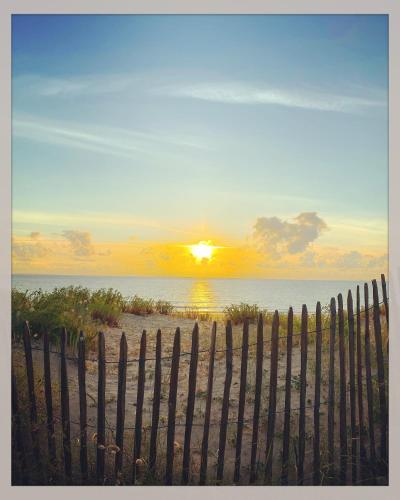 a fence on the beach with the sunset in the background at Hotel Napoleon in Île dʼAix