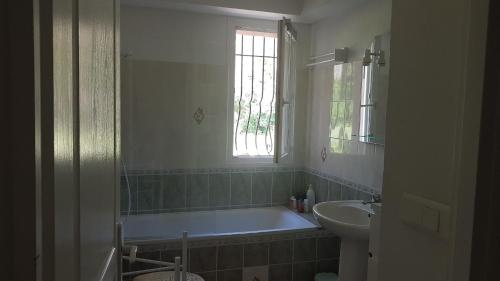 y baño con bañera y lavamanos. en Rez de villa, en Le Beausset