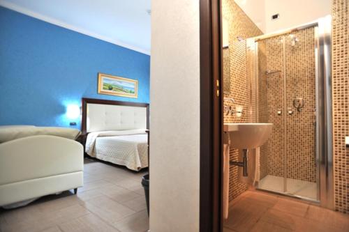 a bedroom with a bed and a bathroom with a sink at Hotel Flora in Noto