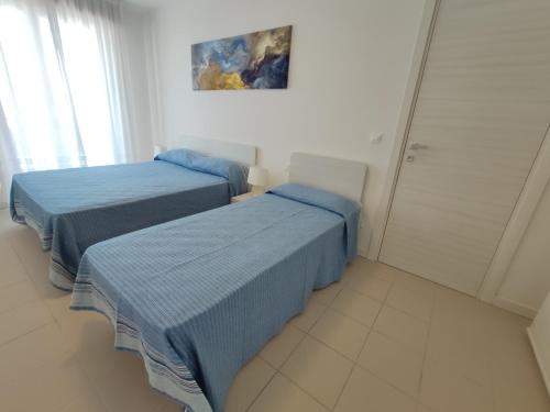 a bedroom with two beds and a painting on the wall at Appartamenti LUNGOMARE SABBIADORO in Lignano Sabbiadoro