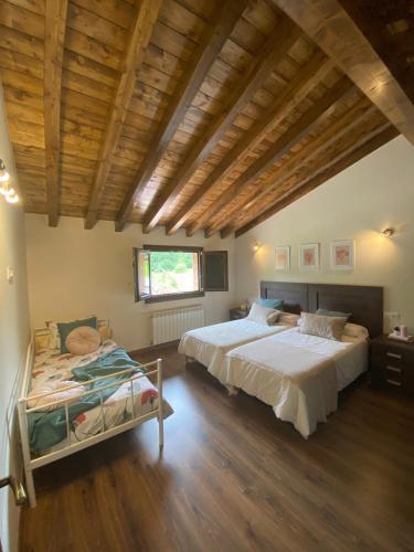a bedroom with two beds and a wooden ceiling at Vivienda Vacacional Del Busto - Ribadesella in Ribadesella