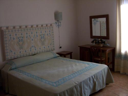 una camera con letto, tavolo e specchio di Bed and Breakfast Santa Maria Oliena a Oliena