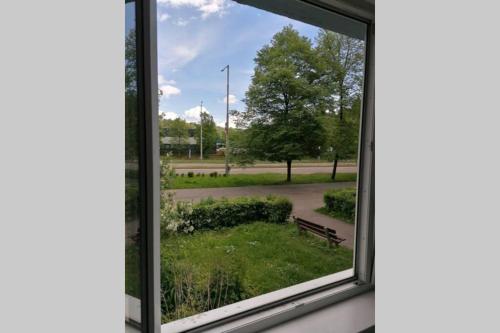a window with a view of a park with a bench at Apartmán blízko hlavnej stanice a centra mesta in Bardejov