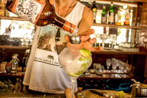 a woman pouring a drink into a martini glass at The Eco Palace Hostel in Búzios