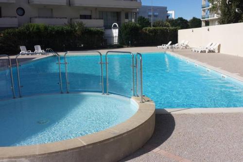 une grande piscine avec de l'eau bleue dans un immeuble dans l'établissement Studio, terrasse, piscine, plage, Les Minimes, à La Rochelle