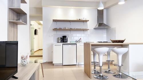 a kitchen with white cabinets and bar stools at apus apartments in Lefkada Town