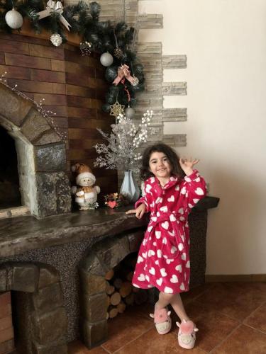 a little girl standing in front of a fireplace at Котедж з неймовірними краєвидами, Карпатський Чан DREAM, Чан Джакузі in Slavske