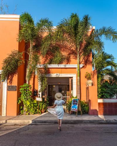 a woman walking down the street in front of a building at Le Muuch Hotel Boutique in Valladolid