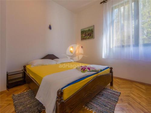 Un dormitorio con una cama amarilla y una ventana en Kuća za odmor LEON, en Klenovica