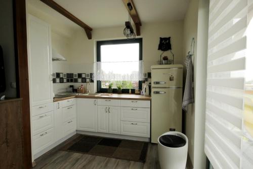 a kitchen with white cabinets and a refrigerator at Bajkowy domek in Lubin