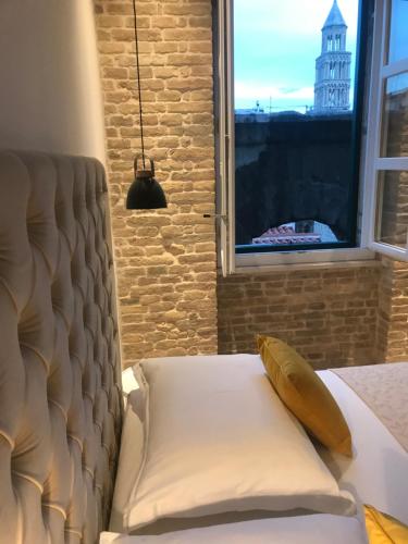 a bed with a pillow and a window with a building at Central Park Residence in Split