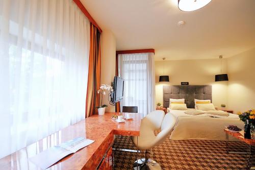 a bedroom with a bed and a desk and a television at DOBRUK APARTAMENTY "Krystyna" w PIĘCIOGWIAZDKOWYM HOTELU Royal Tulip Sand in Kołobrzeg