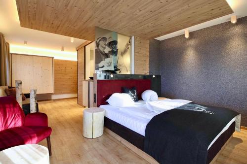 a bedroom with a large bed and a red chair at Hotel Stauder in Dobbiaco